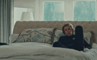 Music video gif. The Kid Laroi in the Selfish Music video lounges on a bed as he sings, “I’m grateful for what you did for me.”