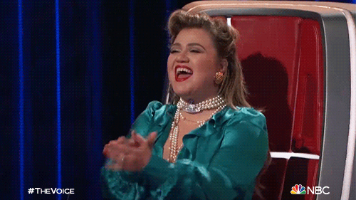 TV gif. On an episode of "The Voice," judge Kelly Clarkson claps and cheers joyfully from her judge's chair.