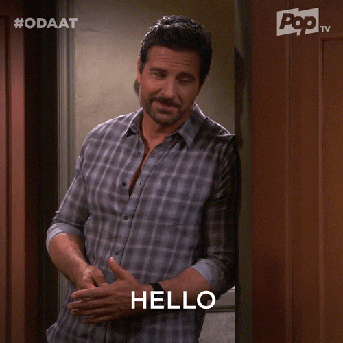 TV gif. Ed Quinn as Max Ferraro in One Day at a Time leaning against a doorway, smiling flirtatiously, and saying "hello."