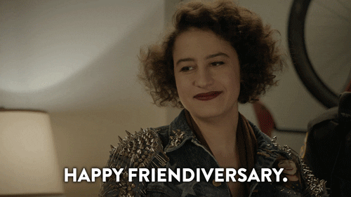 A woman is saying the words, "HAPPY FRIENDIVERSARY" to another woman.