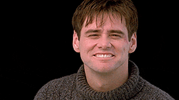 Movie gif. Jim Carrey as Truman Burbank in The Truman Show smiles and leans into a chuckle, laughing at us sweetly but condescendingly.