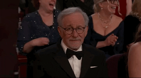 Oscars 2024 GIF. Steven Spielberg exhales a breath while shaking his head. His brows are furrowed and worry is fully plastered all over his face.