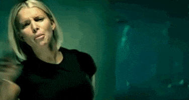 Celebrity gif. Jessica Simpson in a desolate empty room looks furious, sad, and scary, frowning and yelling and shaking her fist, pulling back her hair.