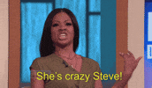Reality TV gif. Steve Harvey winces as a woman yells at him with flailing arms. Text, "She's crazy Steve!"