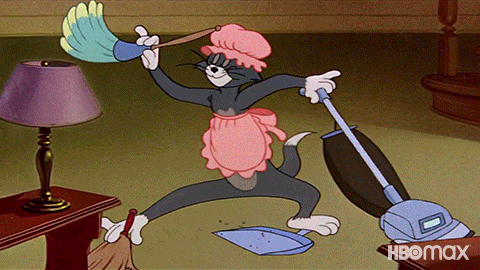 Cartoon gif. Tom from Tom and Jerry wearing a pink ruffly apron and matching bonnet, multitasks, arms and legs moving frantically while dusting and vacuuming and sweeping dirt into a dustpan all at the same time, his face at peace and unworried.