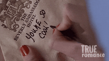 Movie gif. Scene from True Romance. A woman with red nail polish writes a note and a heart on a Beverly Ambassador Hotel napkin that reads, “You’re so cool!”