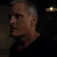Movie gif. Viggo Mortensen as Saul from Crimes of the Future. He sighs and tightens his jaw as he looks around, displeased.