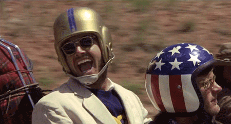 Movie gif. Jack Nicholson as George Hanson in Easy Rider laughs widely while riding in a motorcycle.