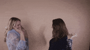 Reaction gif. Two women, one blonde and one with brown hair, face each other and double high-five excitedly.