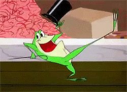 Cartoon gif. Michigan J Frog is doing a jig across the table, kicking his feet up as he raises his hat and cane.