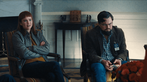 Movie gif. Jennifer Lawrence as Kate and Leonardo DiCaprio as Dr. Randall in Don't Look Up. They're both sitting in separate chairs and Kate has her arms crossed and looks at him in annoyance. Dr. Randall drops his furrowed, stressed face into his hand.