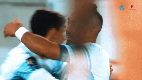 Sports gif. Footballer Dimitri Payet accepts a quick hug from a teammate in celebration, then high-fives and hugs another. 