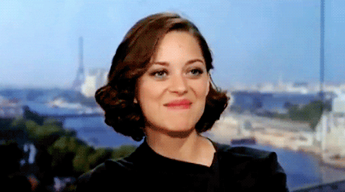 Celebrity gif. Marion Cotillard shyly rocks back and forth while biting her lower lip.