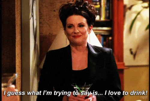 TV gif. Megan Mullally as Karen Walker from Will & Grace looks classy, dressed in a professional blazer with her hair in an updo. She holds a martini glass and forces out a pained laugh while saying, "I guess what I'm trying to say is... I love to drink!"