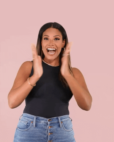 Celebrity gif. Kamie Crawford smiles wide and shimmies as she claps her hands like she's bubbling over with excitement.
