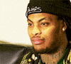 Video gif. A man wearing a beanie and a diamond earring widens his eyes and raises his eyebrows as he says, "Okay..."
