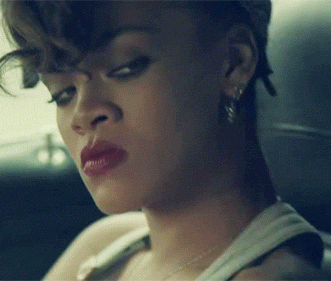 Celebrity gif. Rihanna sits in a car and glares at someone angrily.