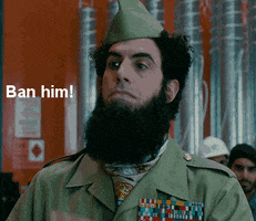 TV gif. Sacha Baron Cohen as Aladeen in The Dictator wears a green military uniform, raising a chin and making a slicing motion with his finger across his throat. Text, "Ban him!"