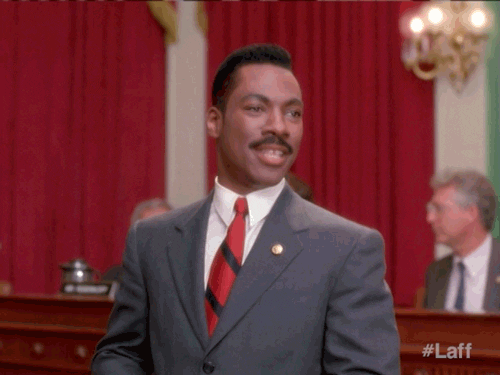 Video gif. Eddie Murphy Leans back, a wide grin on his face, and emphatically claps his hands together as if to say, There we go!