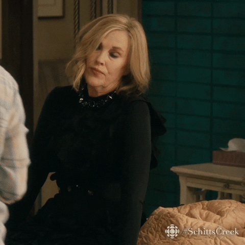 Schitt’s Creek gif. Giving up, a dramatic Catherine O'Hara as Moira rolls her eyes and falls back on her bed.