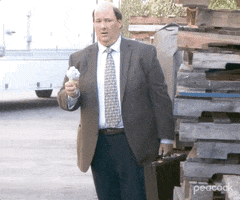 The Office gif. Brian Baumgartner as Kevin holds an ice cream cone and pauses as if shocked as he gazes at something. He remains unmoving as the ice cream topples off the cone.
