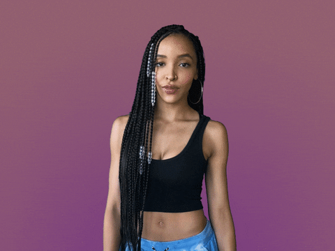 Celebrity gif. Tinashe rolls her eyes and holds her hands up to make a big W as she says, “Whatever.”