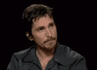 Muppets gif. Christian Bale presses in his lips and blankly nods at Kermit the Frog, who sits across from him and responds with a silent nod.