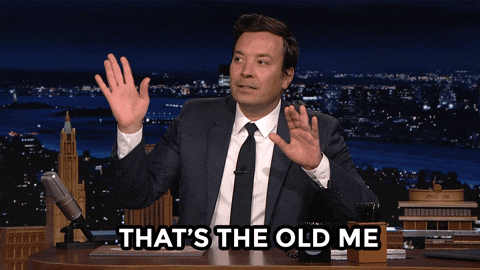 Jimmy Fallon sits on a chair behind a table, waving both of his hands to his left. Text on the screen reads, "That's the old me."