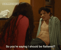 Movie gif from "Challengers." Tashi Donaldson and Patrick Zweig sit on the floor, his shirt is unbuttoned. Caption reads, "So you're saying I should be flattered?"