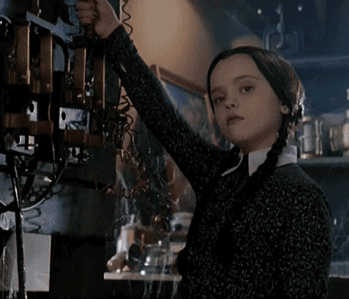 Movie gif. Christina Ricci as as Wednesday Addams from the Addams Family pulls an old electrical lever that sparks as it’s pulled down. She has a bored expression on her face and barely even flinches when the lever sparks near her face.