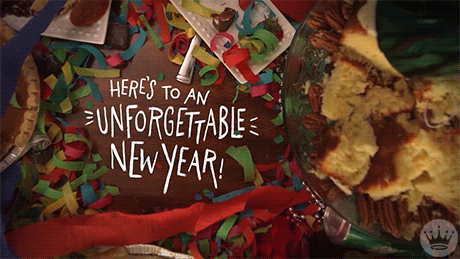 Photo gif. Overhead view of tabletop scattered with crepe paper and colorful confetti, plates of pie, cake, and other desserts; in an empty space on the table, text reads "Here's to an unforgettable new year!"