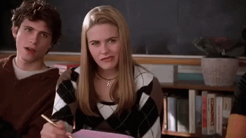 Movie gif. Sitting in a school desk, Alicia Silverstone as Cher in Clueless stares off pensively, blinking and giving a faint smile of recognition.