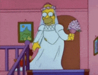 The Simpsons gif. Dressed in a white wedding dress, Homer takes a step down the stairs and pauses to smell his bouquet.