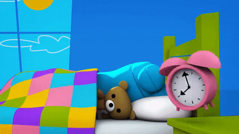 Cartoon gif. Bang the blue robot from StoryBots asleep in bed, under a blanket with a teddy bear, snoozing as their pink alarm clock goes off, keeping their eyes closed as Bang’s arm coming out from under the blanket to slam it off.
