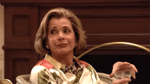 TV gif. Jessica Walter as Lucille Bluth from Arrested Development gives a side-eye to someone offscreen, then rolls her eyes and lifts her martini to take a drink.