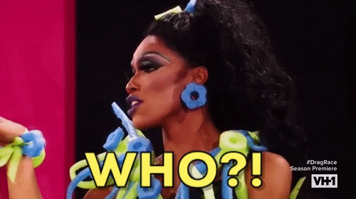 Reality TV gif. A Drag Queen on RuPaul’s Drag Race: Untucked waves their hand side to side and looks fed up. They say, “Who?”