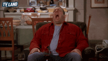 TV gif. Kevin James as Doug on King of Queens sits in an armchair and over-dramatically stretches his arms as he yawns like a lion roaring, then blinks and looks exhausted. 
