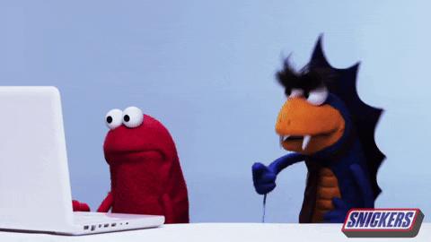 Ad gif. Red puppet works nervously at a laptop while a dragonline puppet stands by his side impatiently, yelling. Snickers logo appears in the bottom corner.