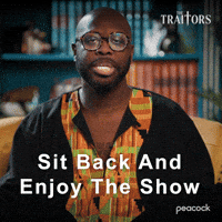 Sponsored gif. Traitors cast member Bob the Drag Queen looks smug as he casually leans back in his chair and says, “Sit back and enjoy the show.”