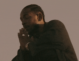 Music video gif. Kendrick Lamar crouching while closing his eyes with his hands in prayer position. He's rapping fiercely, and we can see his neck veins bulge as he lays into his verse.