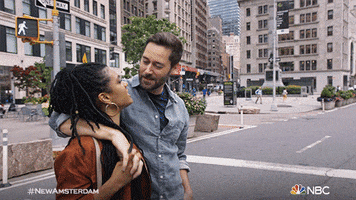 TV gif. Freema Agyeman as Helen and Ryan Eggold as Max in New Amsterdam in the middle of a city street, kissing.