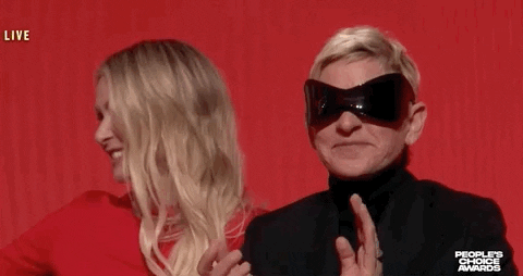 Celebrity gif. Wearing oversized sunglasses, Ellen DeGeneres smiles and claps her hands at the People’s Choice Awards next to her wife, Portia de Rossi.