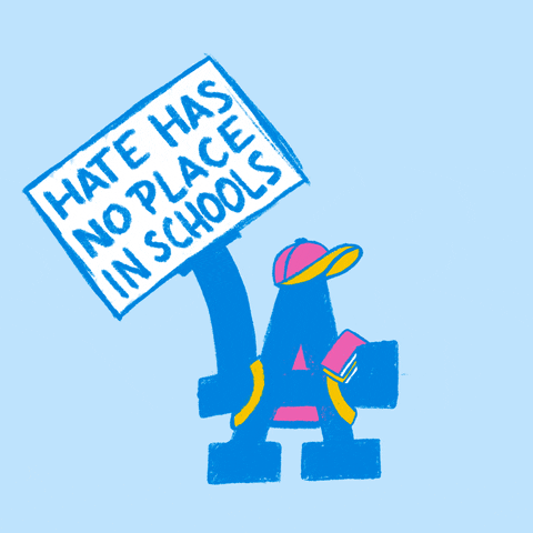 Digital art gif. Blue capital letter A, wearing a pink hat and a backpack, holds a book and waves a sign against a light blue background. The sign reads, “Hate has no place in schools.”