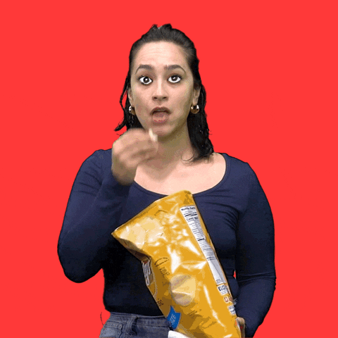 Video gif. Woman shovels chips from a bag into her mouth and chews anxiously while cartoon eyes bug out of her face as she stands in front of a red background.