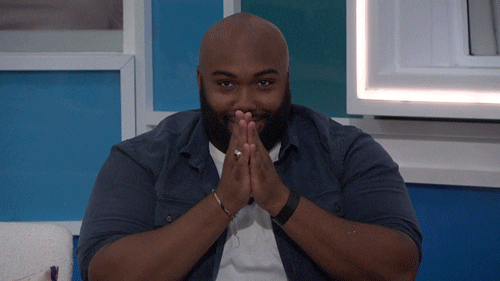 Reality TV gif. A contestant on Big Brother is sitting in a chair and rubs his hands evilly while staring at a person with downturned eyes. He tosses his head up and begins to do an evil laugh while still rubbing his hands together.