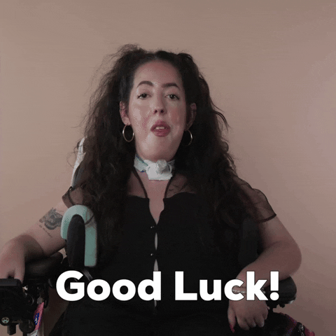 Reaction gif. A Disabled white woman with muscular dystrophy with wavy brown half up half down with two pigtails on top, seated in her motorized wheelchair, says "Good luck!"