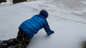 Mother and Son Enjoy Sliding Down Icy Driveway in Memphis
