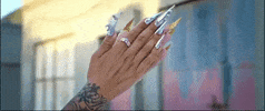 Music video gif. From Rosalía's video for Aute Cuture, two hands with long, sharp chrome nails clap.