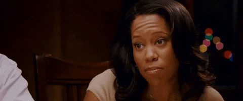 Celebrity gif. Regina King sits at a dining table. She chews with her mouth closed and nods intently. 