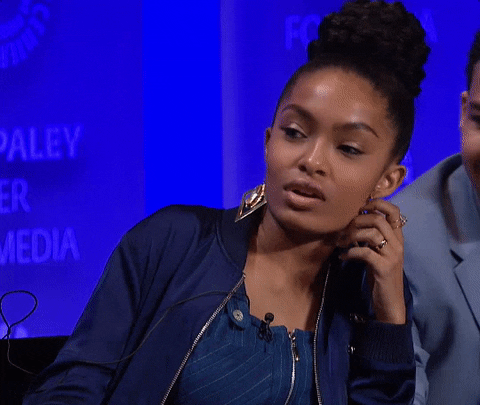Celebrity gif. Yara Shahidi at the Paley Center for Media sits and leans onto the armrest of a chair. She rolls her eyes and huffs out a big sigh, placing her hand on her temple in frustration.